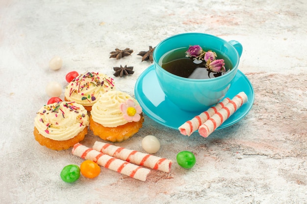 Free photo front view cup of tea with candies and cakes on white desk tea dessert biscuit cake pie