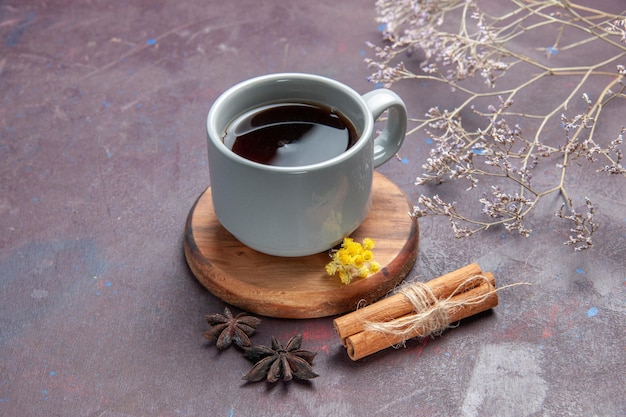Вид спереди чашка чая с корицей на темно-фиолетовом фоне пить чай сладкого цвета