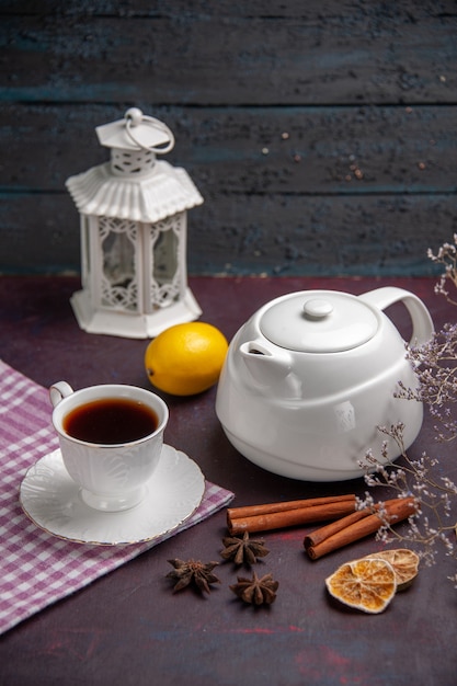 Free photo front view cup of tea with cinnamon and kettle on dark surface tea drink lemon color