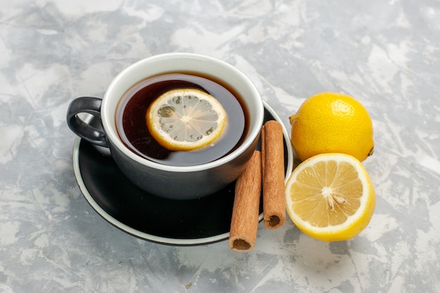 Front view cup of tea with cinnamon and lemon on the white surface