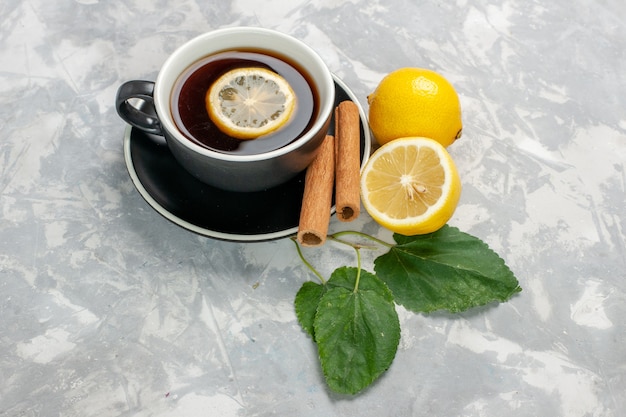 Front view cup of tea with cinnamon and lemon on the white surface