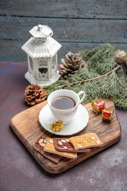 Front view cup of tea with cones and cake slices on dark space