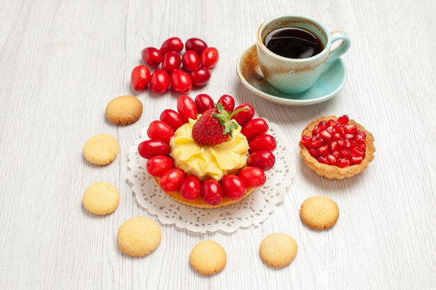 Front view cup of tea with cookies cream cake and fruits on white desk tea dessert cake