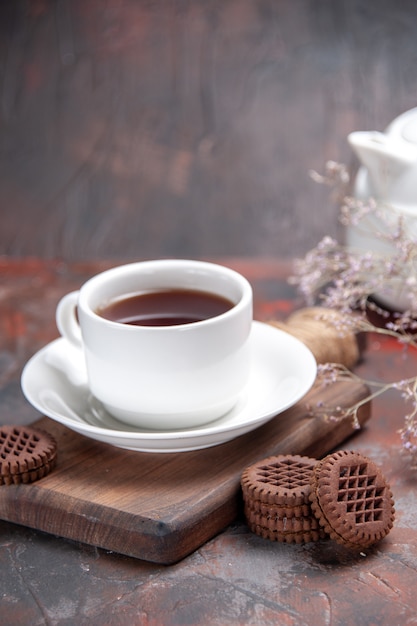 Vista frontale tazza di tè con i biscotti sul biscotto scuro tavolo scuro