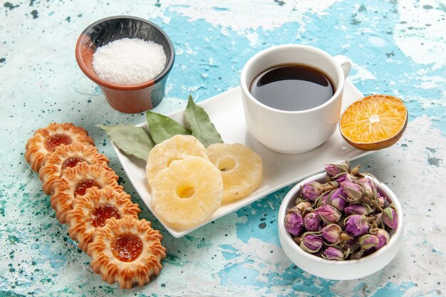 Free photo front view cup of tea with cookies and dried pineapple rings on light-blue surface