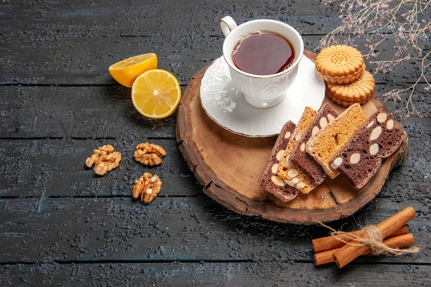 Вид спереди чашка чая с печеньем и фруктами на темном столе церемонии сладкое печенье сахар