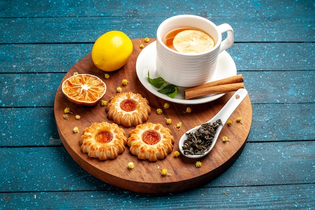 Foto gratuita vista frontale tazza di tè con biscotti e limone sulla scrivania blu