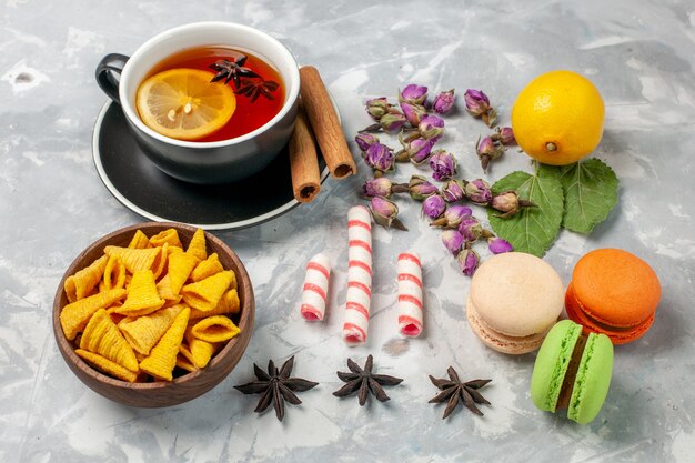 Front view cup of tea with french macarons on light-white desk