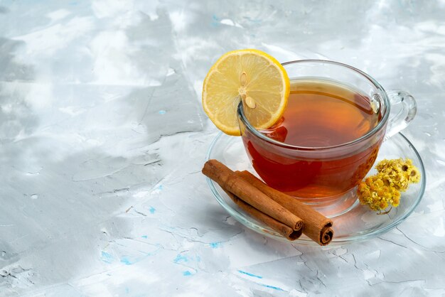 A front view cup of tea with lemon and cinnamon on bright, drink fruit dessert