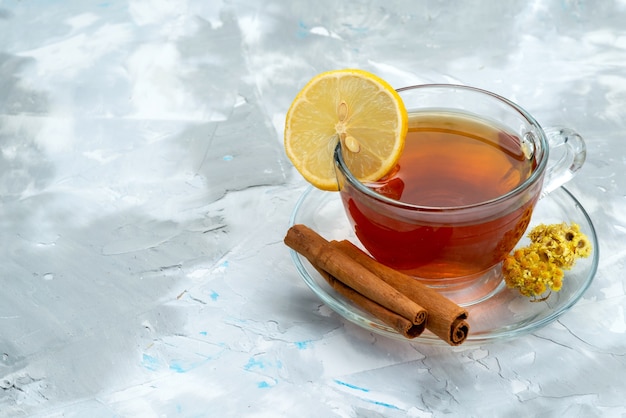 Чашка чая с лимоном и корицей, вид спереди на ярком фруктовом десерте