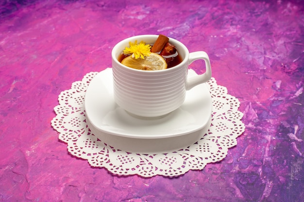 Вид спереди чашка чая с лимоном и корицей на розовом столе конфеты цвета чая