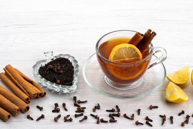 A front view cup of tea with lemon and cinnamon on white, tea dessert candy