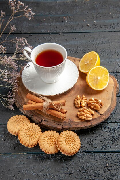 Front view cup of tea with lemon and cookies on dark background