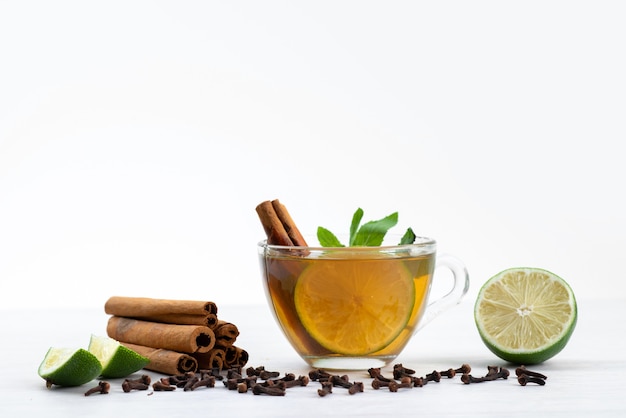 A front view cup of tea with lemon mint and cinnamon on white, tea dessert candy