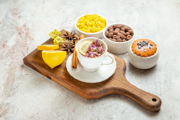 Front view cup of tea with lemon slices and candies on white space