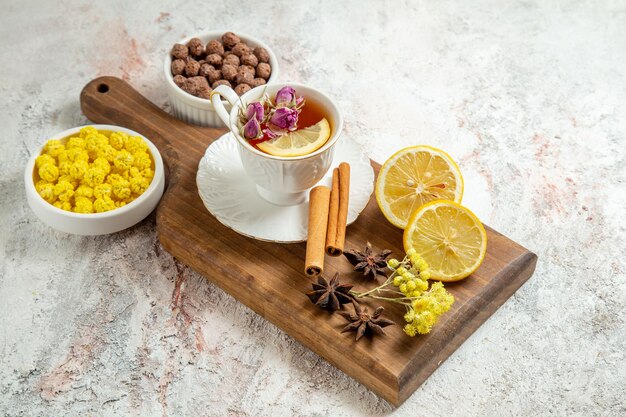 Front view cup of tea with lemon slices and cinnamon on a white space