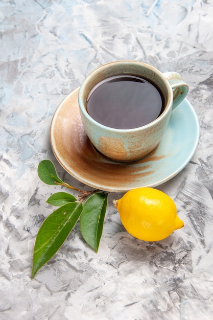 Vista frontale tazza di tè con limone sulla bevanda di tè alla frutta da tavola bianca