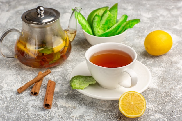 Foto gratuita vista frontale tazza di tè con limoni e cannella sulla superficie bianco-chiaro