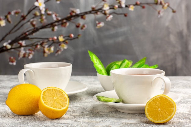 Front view cup of tea with lemons on light white surface