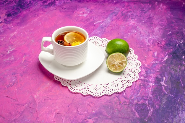 Front view cup of tea with lemons on pink table candy color tea lemon