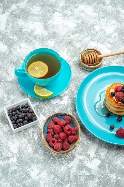 Front view cup of tea with muffins and berries on light table