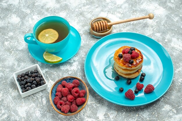 Front view cup of tea with muffins and berries on light table