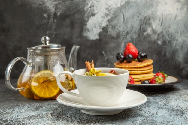 暗い表面の朝の朝食の食べ物にパンケーキとフルーツとお茶の正面図