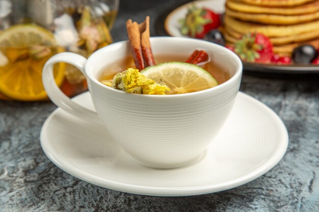 暗い表面の朝の朝食の食べ物にパンケーキとフルーツとお茶の正面図