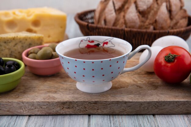 Front view cup of tea with tomato  chicken eggs and olives on a stand