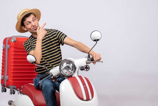 Front view curious young boy with straw hat on moped looking at something