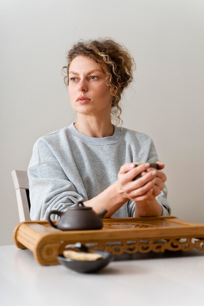 Front view of a curly-haired blonde woman drinking tea and relaxing