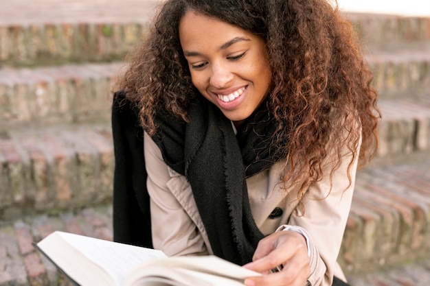 Free photo front view curly woman reading outdoors