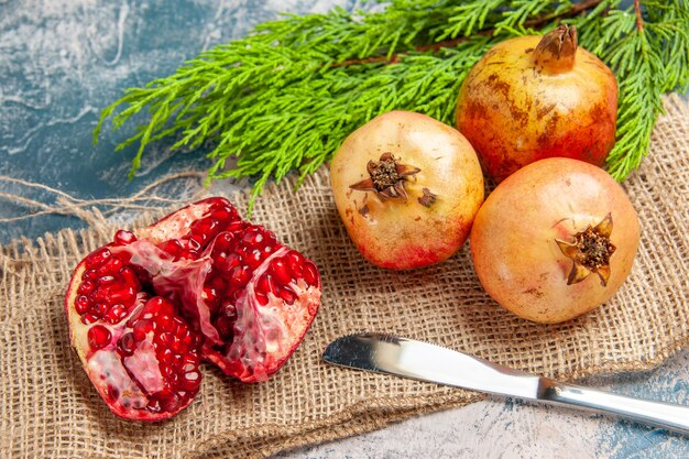 Front view a cut pomegranate pomegranates dinner knife on blue-white