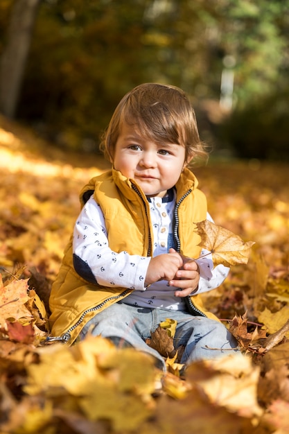 Вид спереди милый ребенок на разноцветных листьях