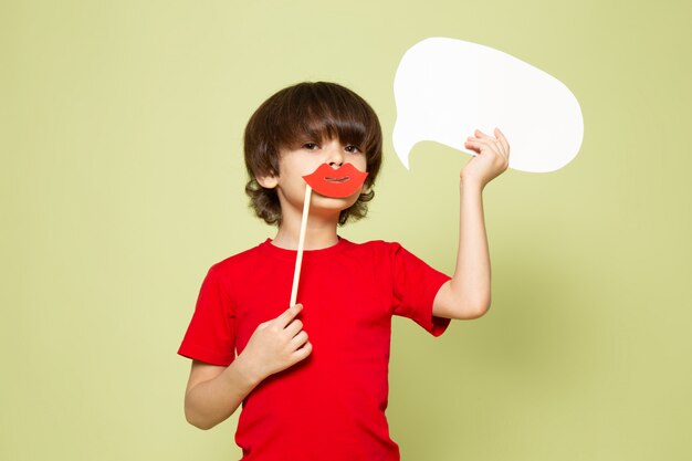 正面のかわいい男の子の愛らしい甘い石の色のスペースに白い看板を持っているスティック唇を保持