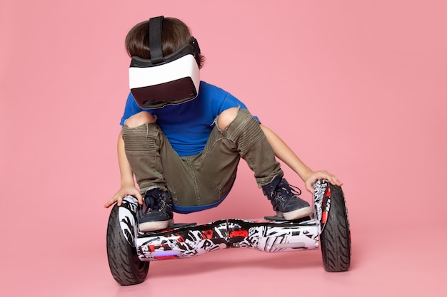 Free photo a front view cute boy in blue t-shirt playing vr on segway on the pink space