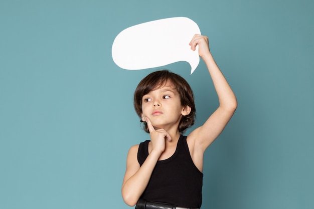 A front view cute boy holding white sign in black t-shirt on the blue space