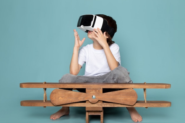 front view cute boy playing vr goggles in white t-shirt on the blue