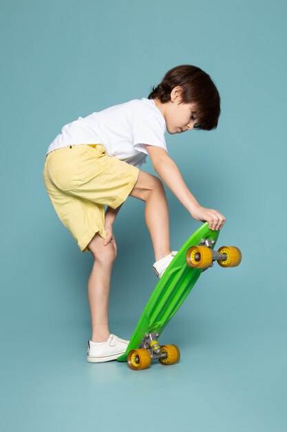 青いスペースに緑のスケートボードに乗って正面かわいい男の子