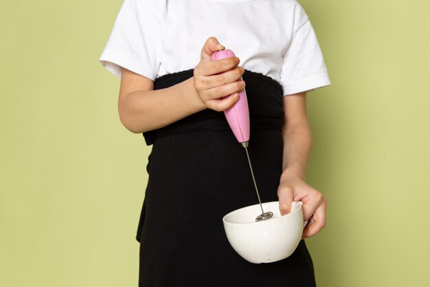 石色のスペースで白いプレート内のコーヒーを準備する白いtシャツで正面のかわいい男の子