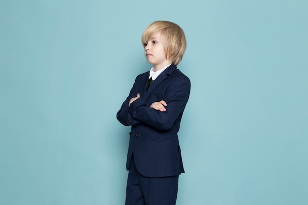 A front view cute business boy in blue classic suit posing business work fashion