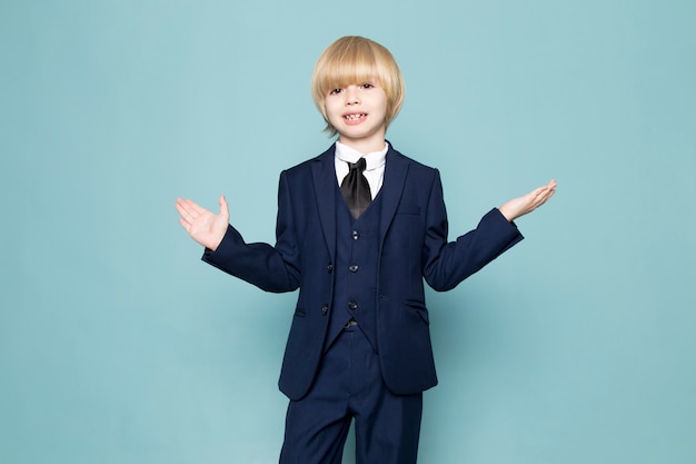 A front view cute business boy in blue classic suit posing business work fashion