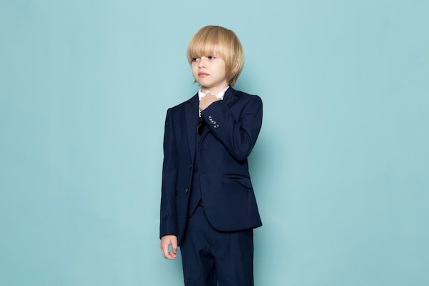 A front view cute business boy in blue classic suit posing business work fashion