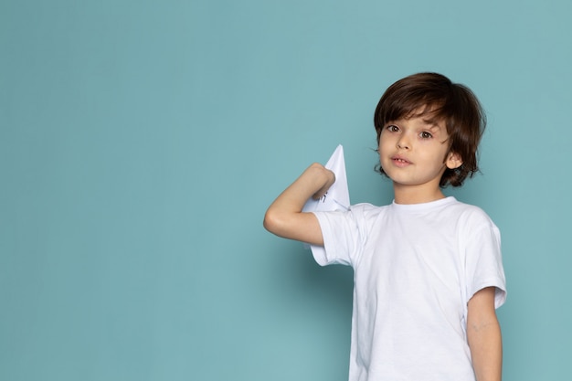 front view cute child adorable sweet holding paper plane on the blue desk