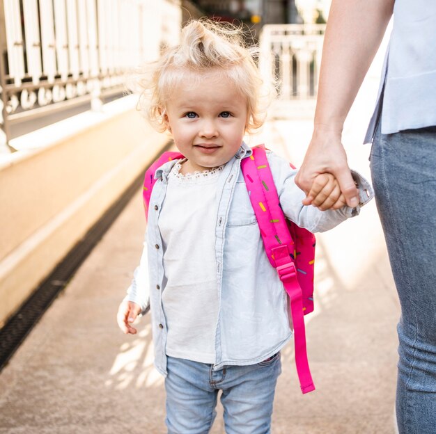 Front view of cute child holding mother's hand outdoors