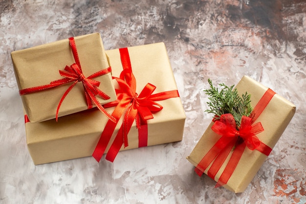 Front view cute christmas presents tied with red bows on a light background