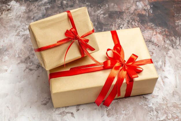 Front view cute christmas presents tied with red bows on light background