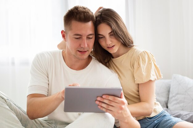 Front view cute couple looking at a tablet