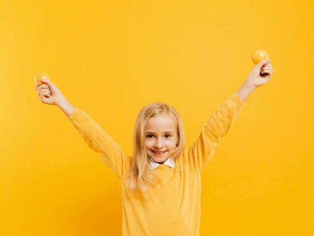 Front view of cute girl posing while holding yellow light bulbs with copy space