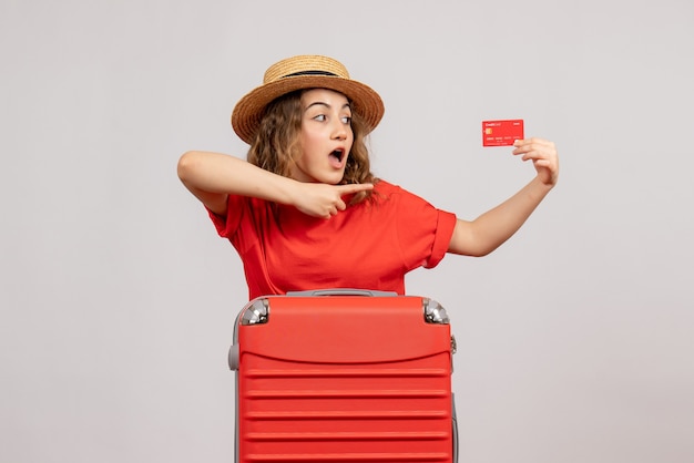 Вид спереди милой праздничной девушки с чемоданом, держащим карту